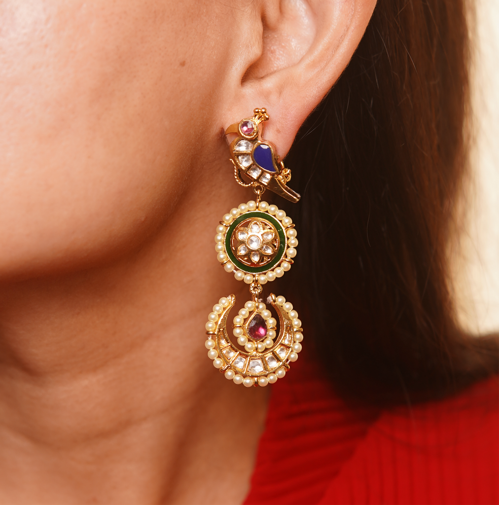 Gold Aarya Earrings with a peacock presented in an ear