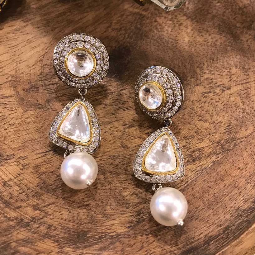 Kundan Earrings With Diamantes And Pearl Drop placed on a wooden stand
