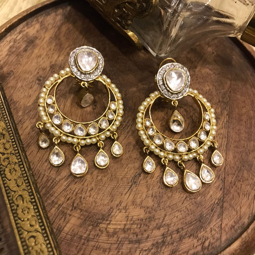 Ezra Earrings from Vasundhara is displayed on a wooden block 